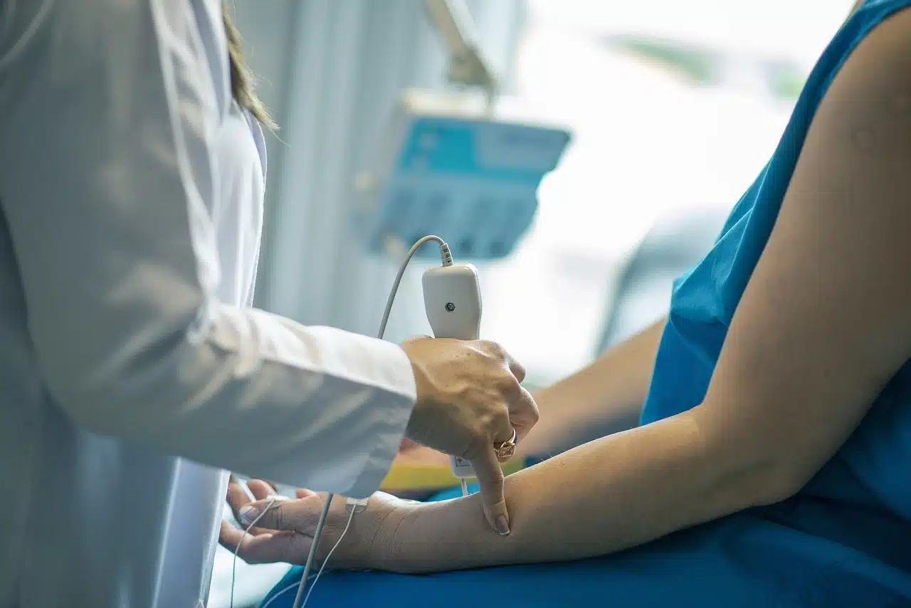 a person in a blue gown holding a device to a person's arm